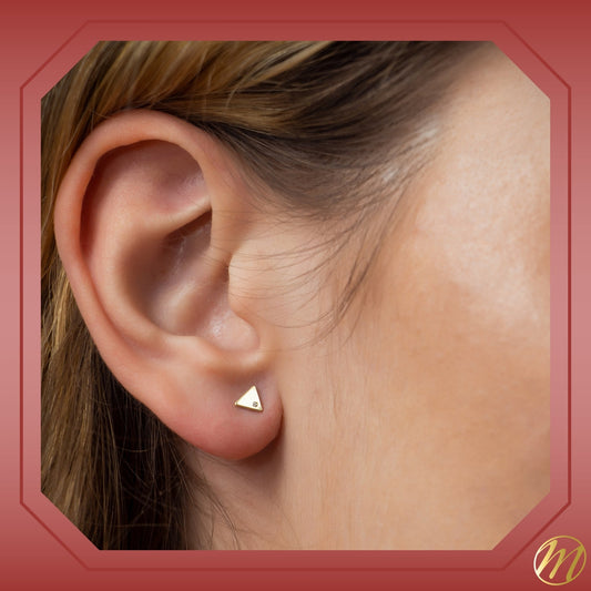 Model wearing 14k yellow gold small flat triangle stud earrings with CZ by Massete