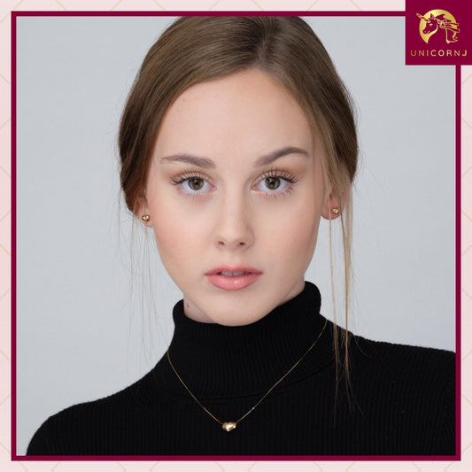 Model wearing 14k yellow gold 6mm puff heart stud earrings by Unicornj