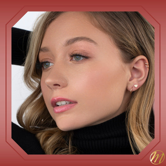 Model wearing 14k yellow gold sunray heart stud earrings with CZ by Massete
