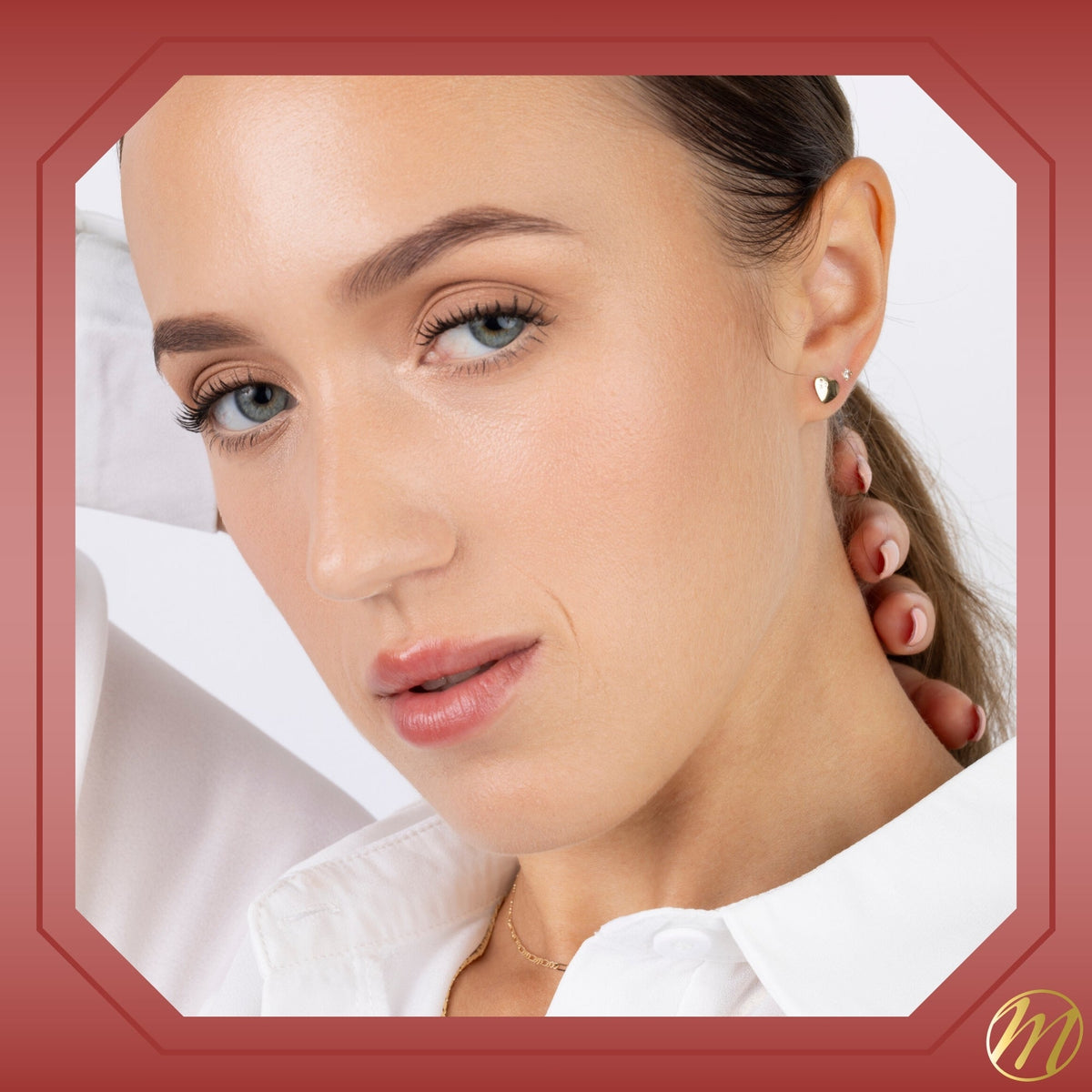 Model wearing 14k yellow gold heart stud earrings with three CZ stones by Massete, view 4