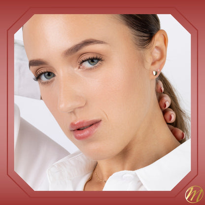 Model wearing 14k yellow gold heart stud earrings with three CZ stones by Massete, view 4
