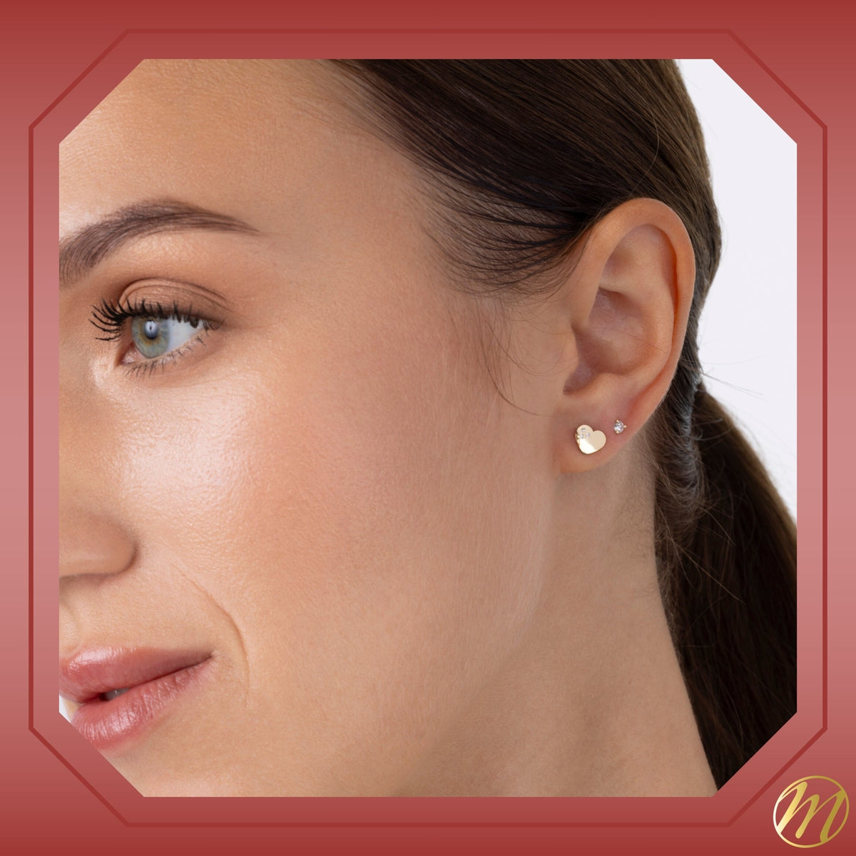 Model wearing 14k yellow gold heart stud earrings with three CZ stones by Massete