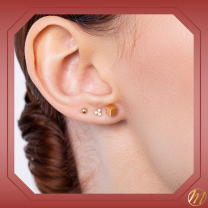 14k yellow gold 4mm cube stud earrings set on an angle by Massete, worn by a model, view 2